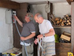 Juin 2016, aidé de Roland, Alain raccorde les fils du tableau à des prises de 220 volt