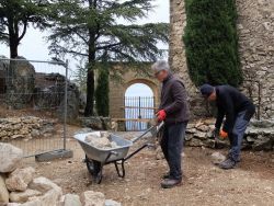 Charly et Pierre chargent la brouette de pierres choisies puis creusent une tranchée sous le porche