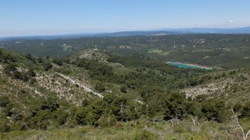 Vue sur le vallon des Reynauds et sa barre rocheuse, au loin, le lac de Bimont.