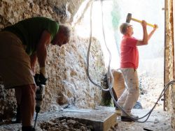 Sauveur attaque l'épaisse dalle en béton au percuteur. Il sera relayé par Jacques, à la masse.