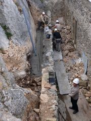 Nicolas et Joan apportent le béton à Hafedh, à l'aide d'une brouette puis de seaux. Au premier plan, Maxime, le conducteur des travaux.