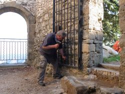 Alain taille les pierres qui empêchent la porte de se rabattre bien contre le mur