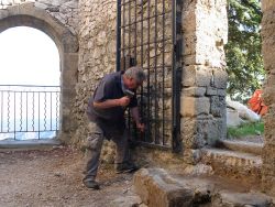 Alain taille les pierres qui empêchent la porte de se rabattre bien contre le mur