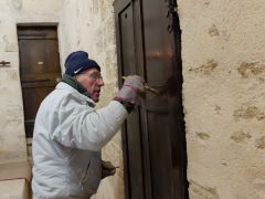 Alain H. passe une couche de lasure sur la porte.