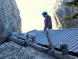 Nicolas passe les seaux de béton à Flavien qui recouvre le chaînage