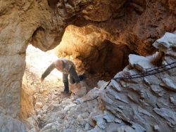 Derrière Alain, le jour passe par l'ouverture de l'aven en falaise 