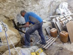 Dans la cave, Daniel fixe le cadre au rocher