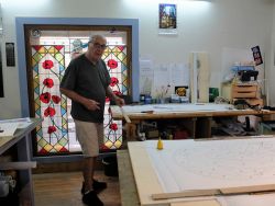 Daniel prépare le fond du vitrail 3 en clouant des baguettes de bois tout autour.