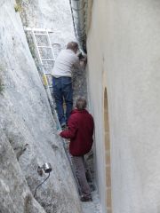 Derrière le cloitre, Laurent fait des essais. Le coude doit relier la gouttière au tuyau de fonte