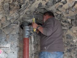 Dans le local Elzéar, le tuyau et le coude sont bien en place dans le jambon soudé au sommet de la descente d'eau. Jean colle le raccord